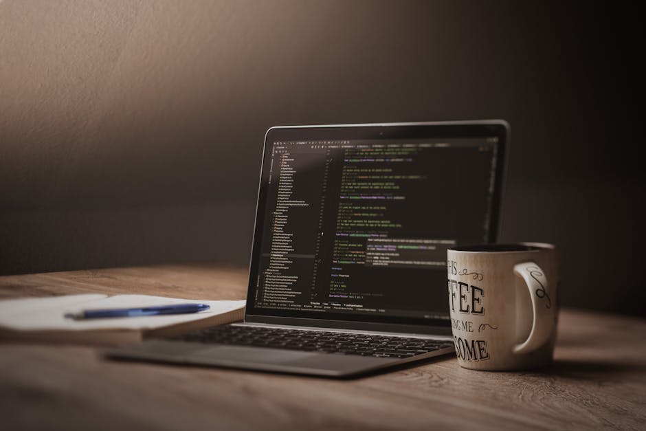 Laptop con codice di sviluppo software e tazza di caffè su scrivania in legno — uso dell