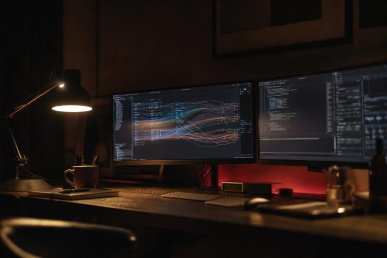 Postazione di lavoro notturna con monitor che mostrano flussi di codice e agenti AI in dialogo — architettura multi-agente per PMI italiane 2026