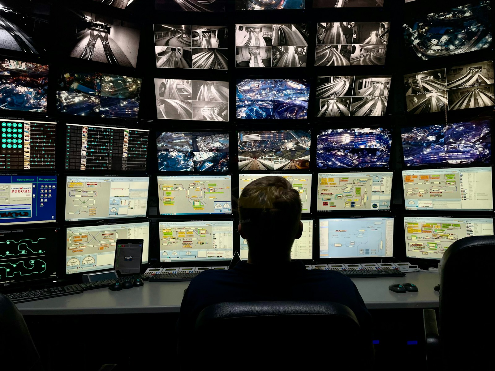 Operatore davanti a sei monitor neri che mostrano dashboard, codice e flussi di dati — agenti AI che lavorano su sistemi aziendali per PMI italiane