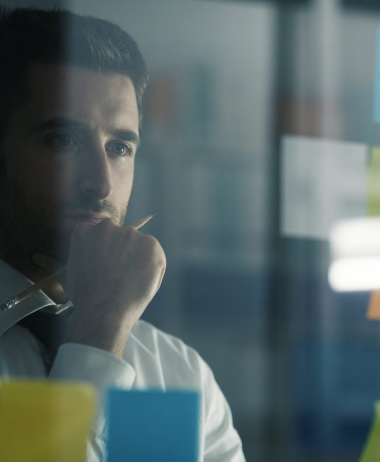 Creative business solutions and strategy Business executive reading sticky notes on a glass, he is thinking about creative business solutions and strategies